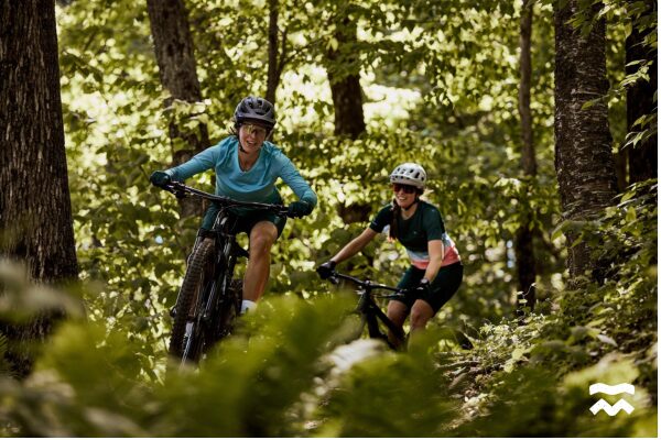 Deux femmes souriantes à vélo à Bromont, montagne d'expériences