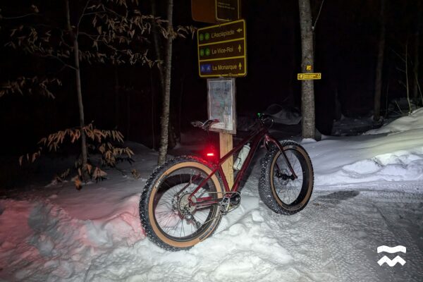 Gros plan d'un fatbike le soir à une intersection de sentiers au Parc national du Mont-Orford