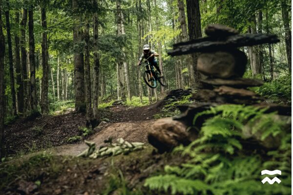 Un homme en vélo de descente au Wolf Bike Park, en train de faire un saut